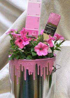 a paint can with pink flowers in it and a brush sticking out of the top