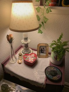 a table topped with a lamp next to a vase filled with flowers and other items