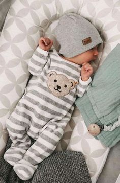 a baby laying on top of a bed wearing a hat