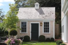 a small house with a white roof and black shutters on the front door is shown