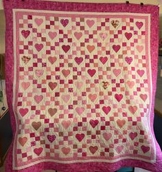 a pink and white quilt with hearts on it