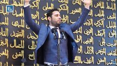 a man standing at a podium with his hands in the air while wearing a suit and tie