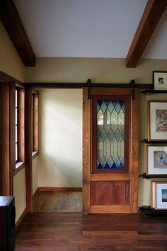 an empty room with wood flooring and framed pictures on the wall next to a wooden door