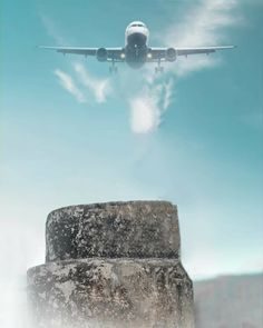 an airplane flying over a stone structure in the sky