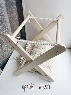 a wooden chair sitting on top of a white table next to a window with the words upside down written below it