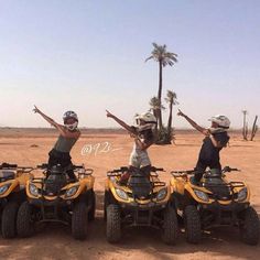 three people on four wheelers in the desert