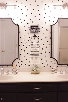 a bathroom with polka dot wallpaper and two sinks in front of the vanity mirror