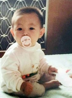 a baby with a pacifier in its mouth sitting on a bed