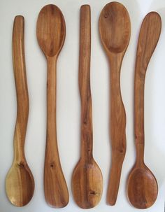 four wooden spoons and two wood spatulas on a white surface with the same design