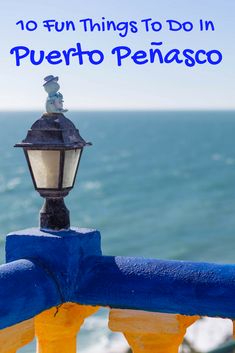 a street light sitting on top of a blue and yellow railing next to the ocean