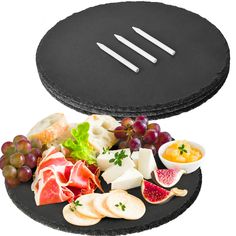 an assortment of cheeses, meats and fruit on a black platter