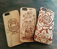 three wooden iphone cases with designs on them