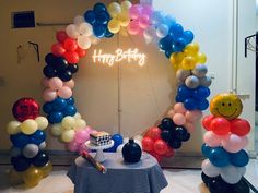 a birthday party with balloons, cake and balloon arch in the shape of smiley face