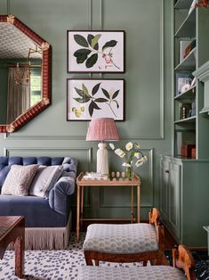 a living room with green walls and blue couches in the corner, two paintings on the wall