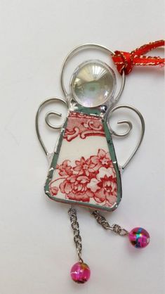 a glass angel ornament hanging from a red and white ribbon on a white background