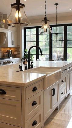 a large kitchen with an island in the middle and two lights hanging from the ceiling