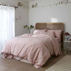 a bed with pink sheets and pillows in a bedroom