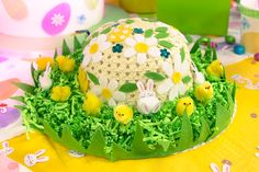 there is a cake decorated with flowers and rabbits on the grass in front of it