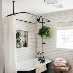 a bathroom with a black and white bathtub next to a window filled with greenery