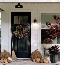 the front porch is decorated for fall with pumpkins and gourds