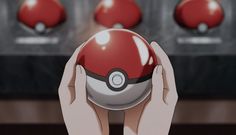 someone is holding up a pokemon ball in front of some red and white balls on a table