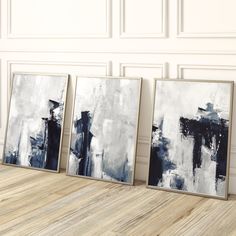 three abstract paintings on the wall in an empty room with wood flooring and white walls