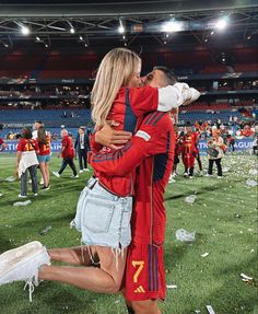 a man and woman kissing on the field at a soccer game with confetti all around them