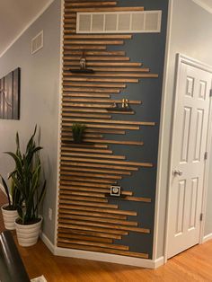 a room with a wooden slatted wall and potted plants