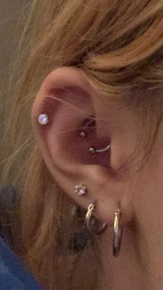 a close up of a person's ear with three different piercings on it