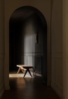 an empty room with a wooden table in the center and dark walls on either side