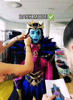 a man is getting his face painted by another person in the background with text that reads dark mode v