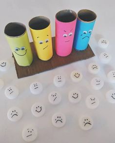 four different colored cups with faces drawn on them and some white balls in the middle