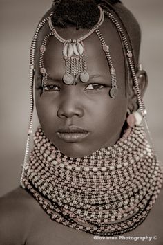 a black and white photo of a woman with beads on her head