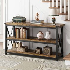 a book shelf with books and vases on it in front of a stair case