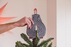 a person holding a paper cut out of a woman on top of a christmas tree