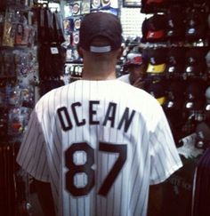 a man in a baseball uniform is looking at items on the wall behind him that are for sale