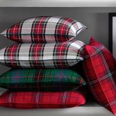 four plaid pillows stacked on top of each other in front of a black framed photograph