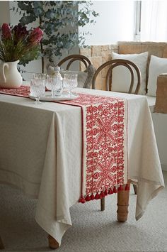 a table with a red and white table cloth on it, next to two chairs