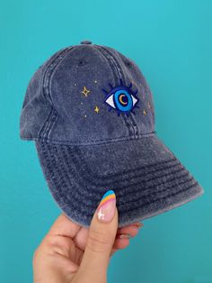 a person holding up a denim hat with an eye on the front and stars on the side