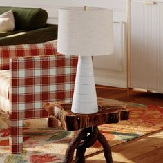 a table lamp sitting on top of a wooden stand in a living room next to a couch