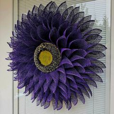 a purple and yellow sunflower hanging on the side of a building with shutters