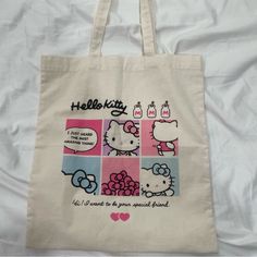 a hello kitty tote bag on a bed with white sheets and pink hearts in the background