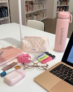 an open laptop computer sitting on top of a white table next to a pink bag