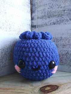 a blue crocheted stuffed animal sitting on top of a wooden table