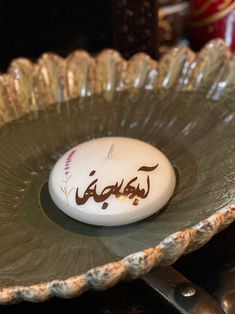 a white candle sitting on top of a glass bowl