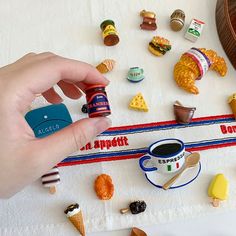 a person is holding a small cup in front of some miniature food on a table