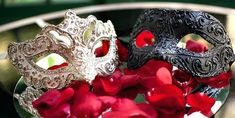 two masquerade masks sitting on top of red roses