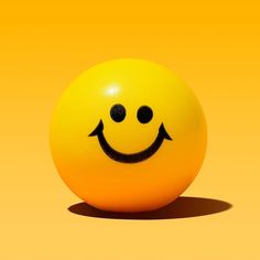 an orange ball with a smiley face drawn on it's side, sitting in front of a yellow background