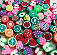 there are many different types of buttons on this white surface, including apples, watermelon, oranges and kiwi