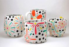 four coffee mugs with designs on them sitting next to each other in front of a white background